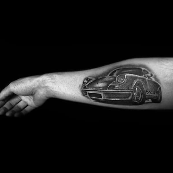 Realistic black Porsche tattoo placed on the forearm, emphasizing smooth curves and detailed wheels.