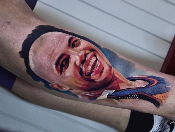 Realistic color portrait tattoo of a smiling basketball player, featuring detailed shading, vibrant tones, and lifelike facial expression.