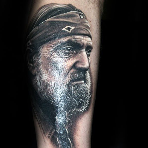 Hyper-realistic tattoo of an older man with a bandana, braided beard, and contemplative expression