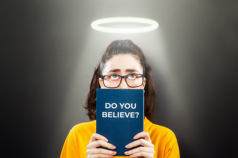 portrait of a woman holding a book while looking up above religious concept