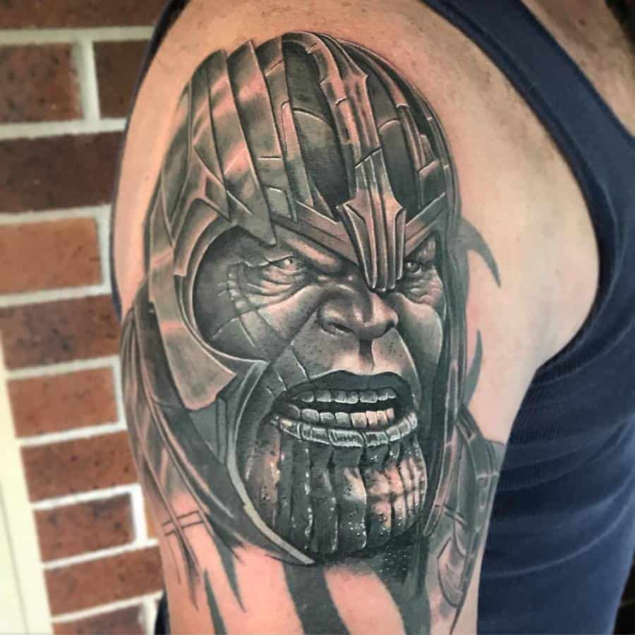 A realistic black and gray Thanos tattoo on the upper arm, featuring intense shading and intricate details