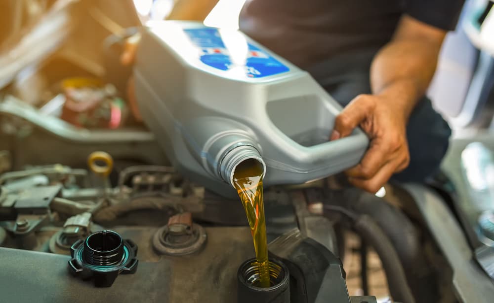 car mechanic replacing and pouring fresh oil into engine