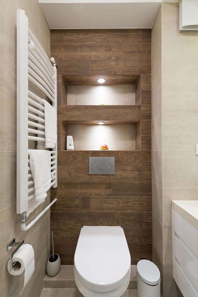 Small bathroom with wall-hung toilet, recessed wood shelves, and towel radiator.