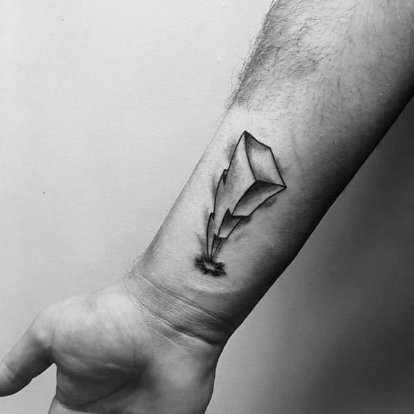 Minimalist black Power Rangers lightning bolt tattoo on the inner forearm, featuring fine lines and subtle shading.