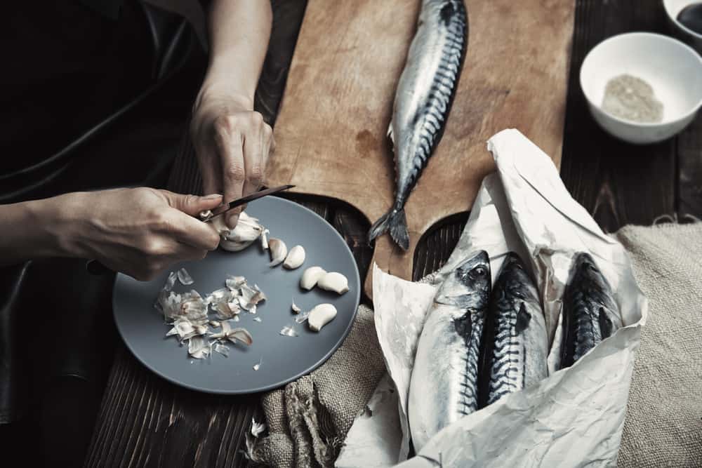 woman preparing mackerel fish for cooking