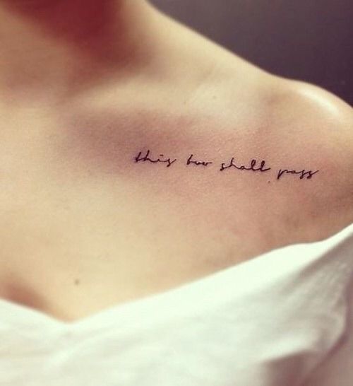 A "This Too Shall Pass" tattoo in cursive, on the collarbone area of a person's shoulder.