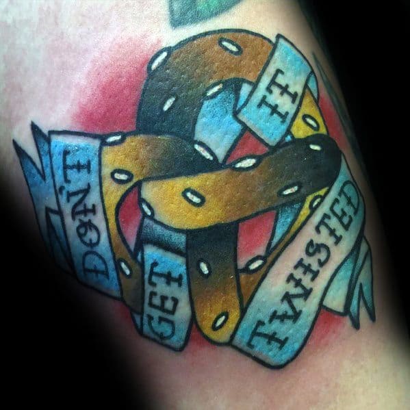 Colorful pretzel tattoo wrapped in a blue ribbon with the phrase "Don't Get It Twisted," featuring bold outlines and shading for depth.