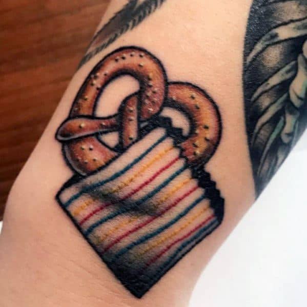Pretzel tattoo in a striped paper bag, featuring bold outlines, rich shading, and a classic snack stand aesthetic for a nostalgic feel.
