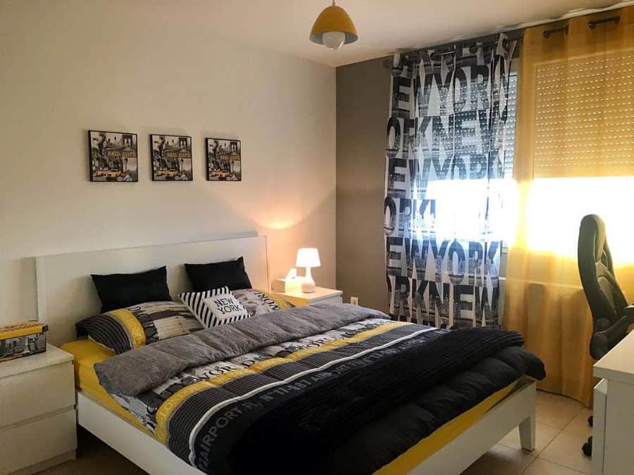 New York-themed bedroom with graphic curtains, matching bedspread, and wall art.