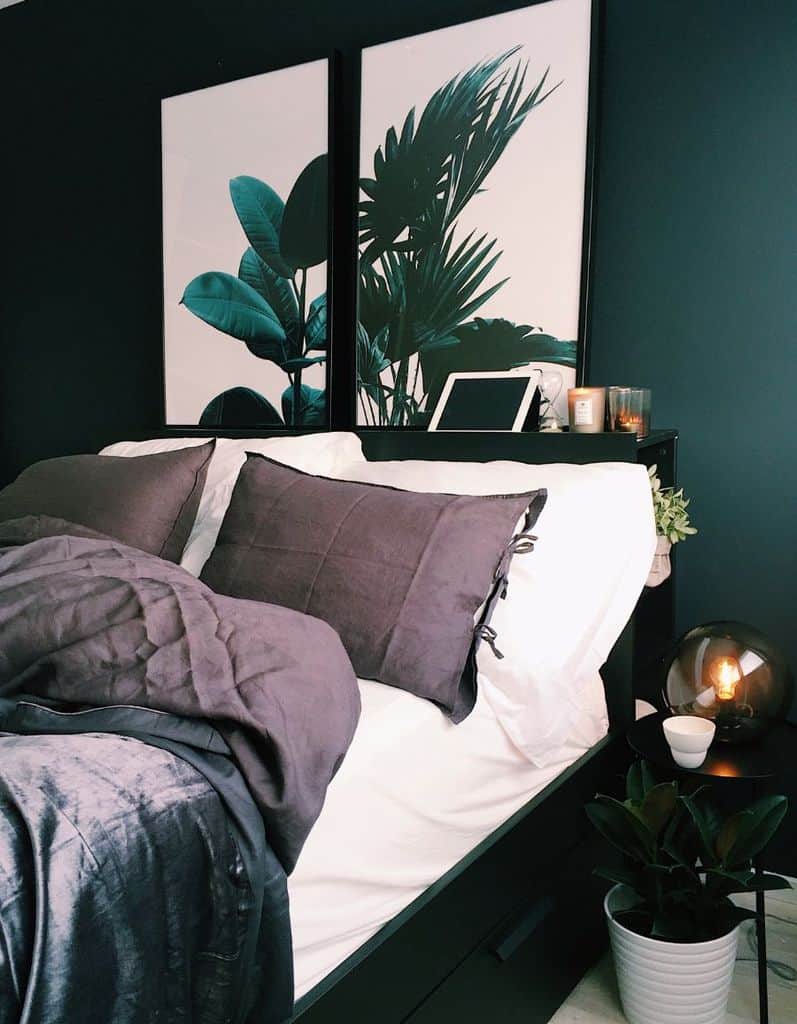 Modern bedroom with green walls, framed plant artwork, and potted greenery.