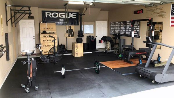 Garage gym with lifting platform, treadmill, rowing machine, pull-up bars, and Rogue equipment.