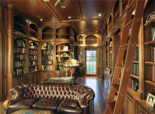 Luxurious wood-paneled library with bookshelves, a leather sofa, a ladder, and a chandelier