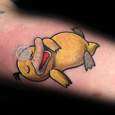 Adorable Psyduck tattoo lying down asleep with a bubble from its nose, capturing a peaceful and funny moment on a man's arm.