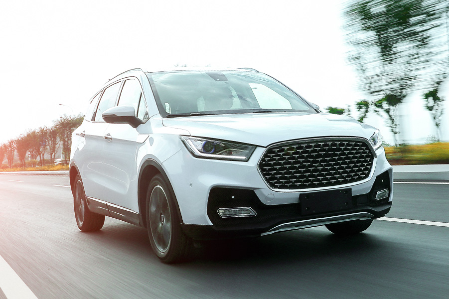 A white SUV speeds down the road with blurred trees behind, highlighting real tire performance in motion