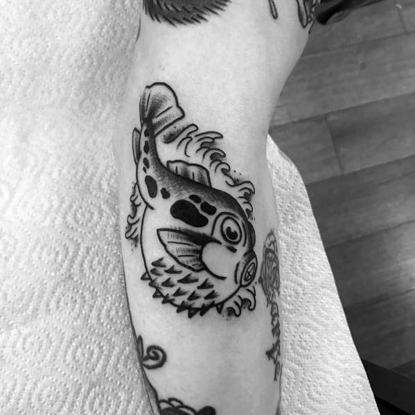 Black and grey pufferfish tattoo with bold outlines, solid shading, and wave details, giving it a classic and dynamic traditional look.