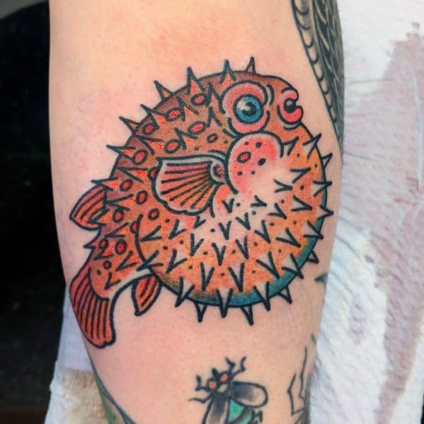 Traditional-style pufferfish tattoo with bold outlines, vibrant orange shading, and intricate spike details, creating a classic and playful look.