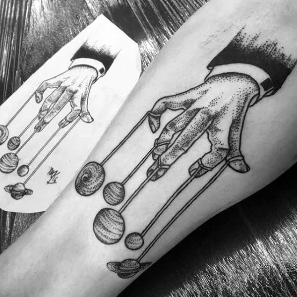 Dotwork puppet tattoo of a hand in a suit controlling planets with strings, symbolizing cosmic influence or control over the universe.