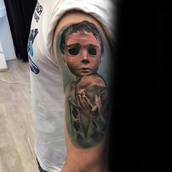 Realistic puppet tattoo of a childlike marionette with hollow eyes holding a mask, symbolizing hidden identity or emotional concealment.