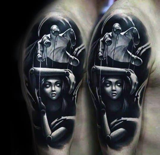 Realistic black and grey puppet tattoo of a hooded figure controlling a serene female marionette, symbolizing hidden control and suppressed identity.