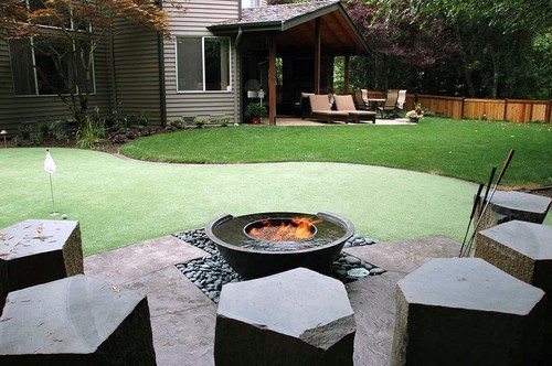 Backyard with a putting green, modern fire pit, and a cozy covered seating area.