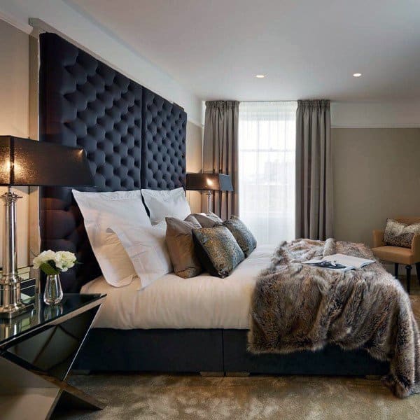 Luxurious bedroom with tufted headboard, black lamps, and fur throw on bed.