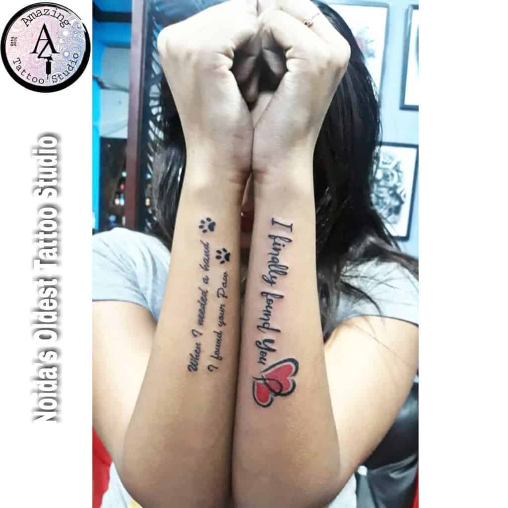 Forearm tattoos with heartfelt quotes, paw prints, and a red heart, symbolizing love and connection with a pet