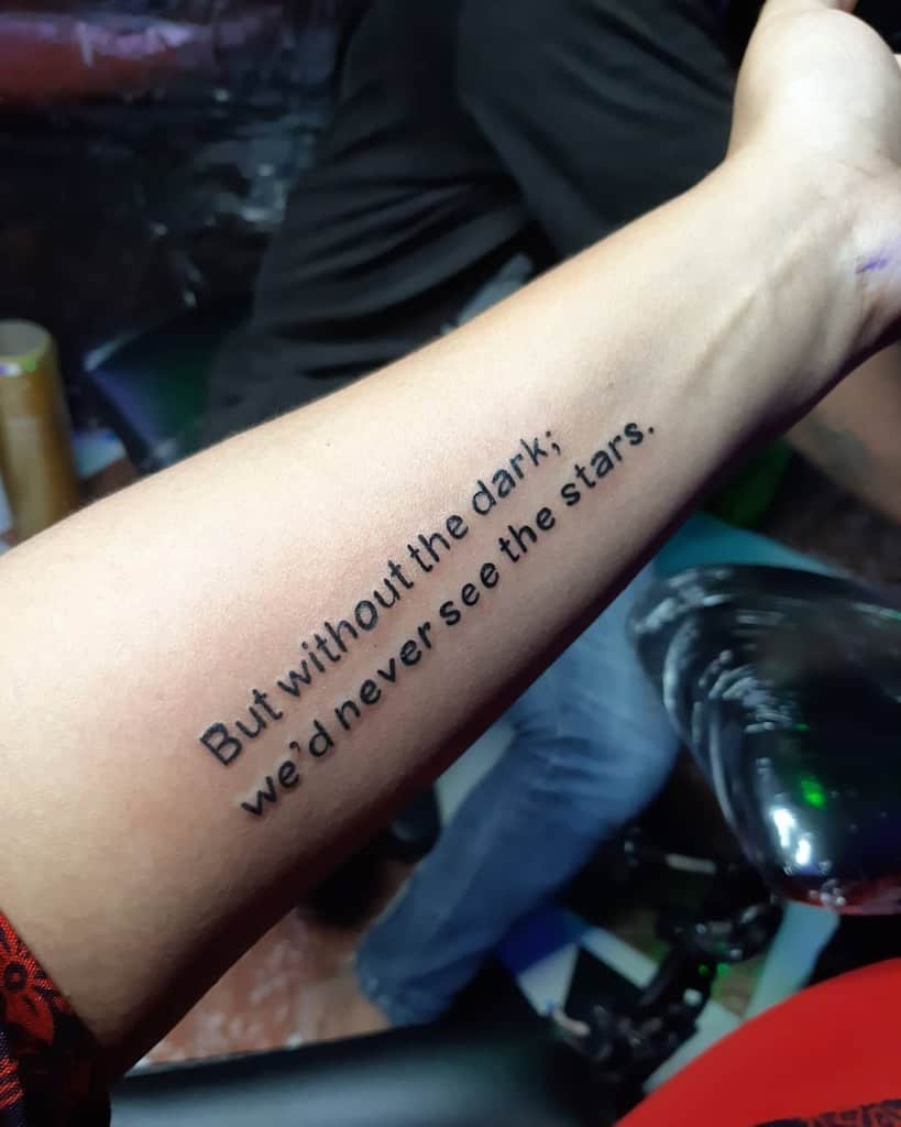 Forearm tattoo that reads, "But without the dark, we'd never see the stars"