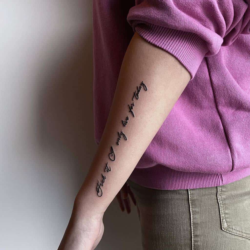 Simple cursive forearm tattoo with the motivational quote 'Fuck it, I only live for today,' embodying a carefree attitude