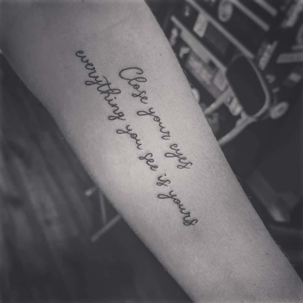 Tattoo on the forearm that reads "Close your eyes everything you see is yours"