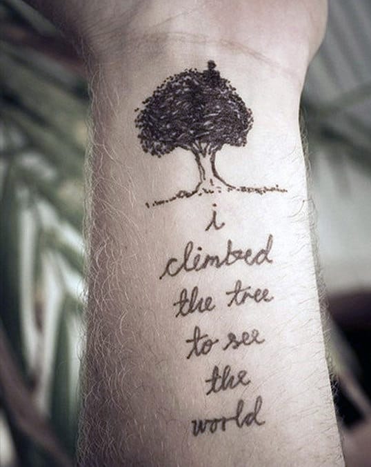 Tattoo of a tree with the text "I climbed the tree to see the world" on a forearm