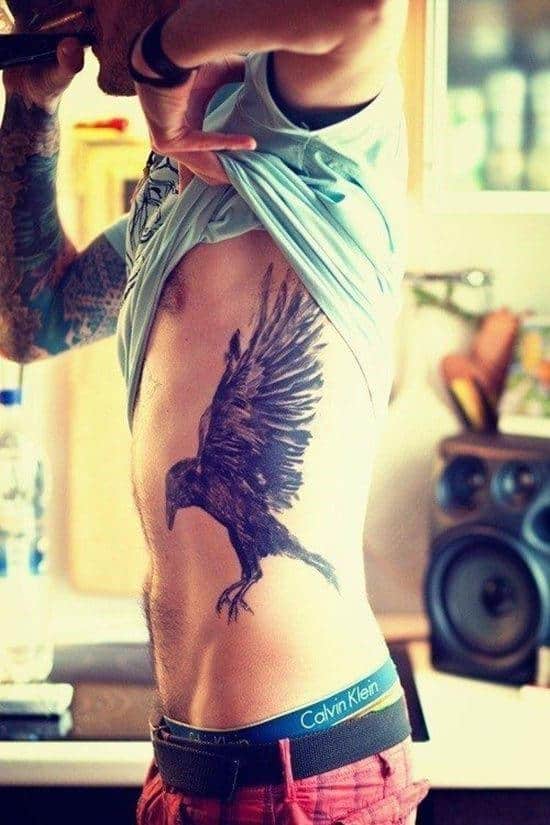 Person revealing a large raven tattoo on their side torso