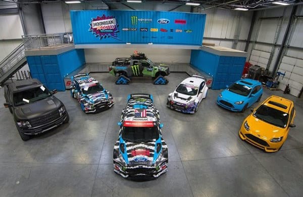 Racing-themed garage showcasing vibrant rally cars, a monster truck, and bold team branding.