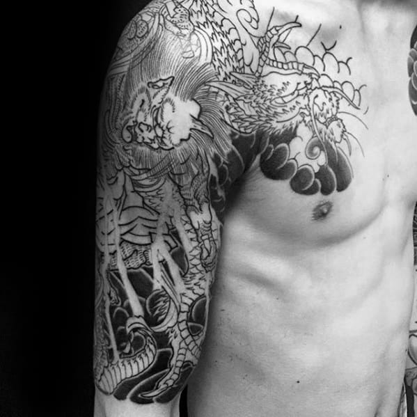 Black and grey Japanese-style sleeve tattoo in progress with detailed dragon, bold clouds, and intricate linework extending across chest.