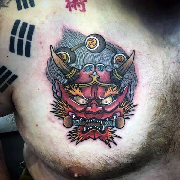 Vibrant Raijin chest tattoo with fierce red mask, golden horns, thunder drum, and dynamic shading in bold Japanese style.