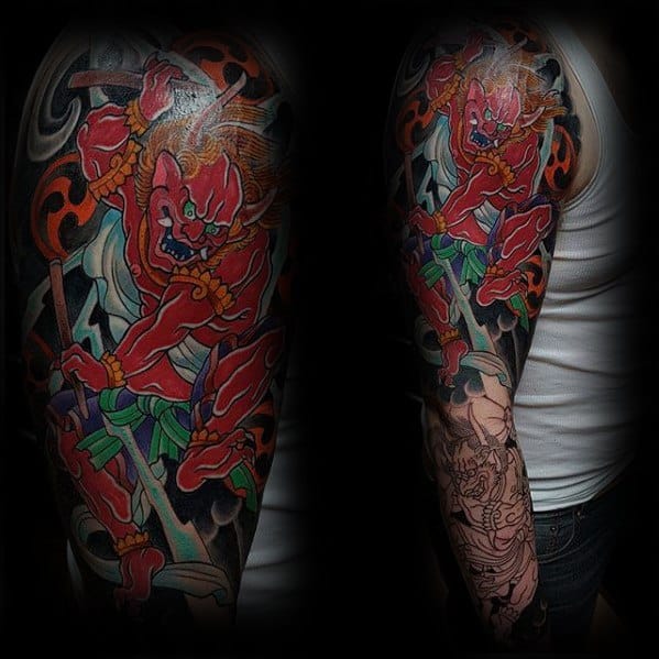 Fierce Raijin upper sleeve tattoo with vivid red thunder god, wild hair, dynamic pose, and bold black and orange background.
