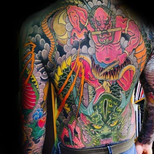 Vibrant Raijin full back tattoo featuring red thunder god with drumsticks, bold lightning, swirling clouds, and a fierce green dragon.