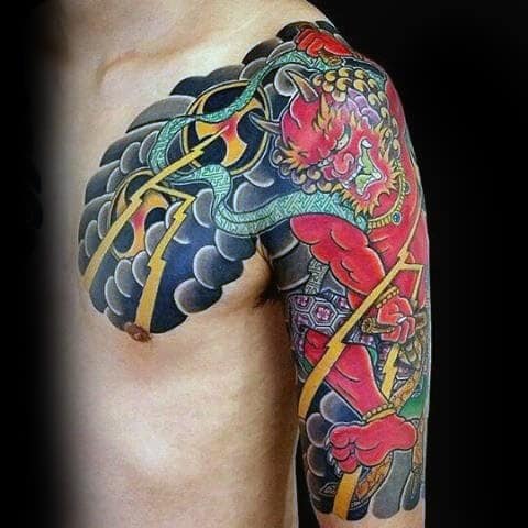 Bold Raijin shoulder and arm tattoo with red thunder god, golden lightning, swirling black clouds, and intricate Japanese detailing.