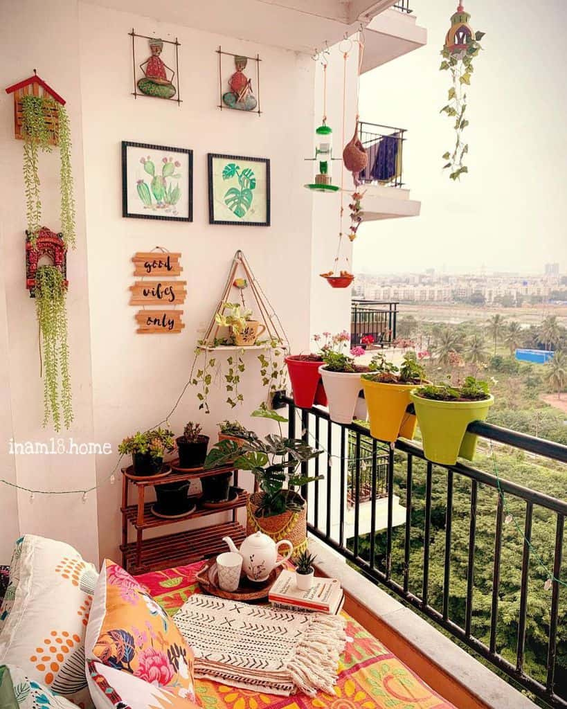 Colorful small balcony garden with potted plants, hanging decor, and vibrant railing planters.