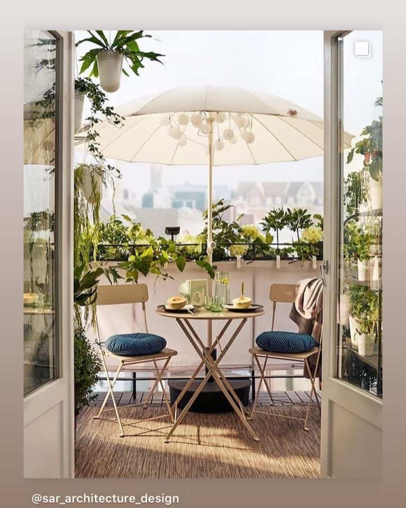Beautiful outdoor balcony with a small dining set, umbrella, potted plants, and cozy decor.