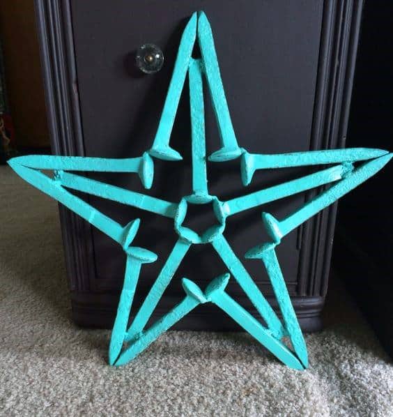 Turquoise metal star decoration leaning against a dark piece of furniture on a carpeted floor