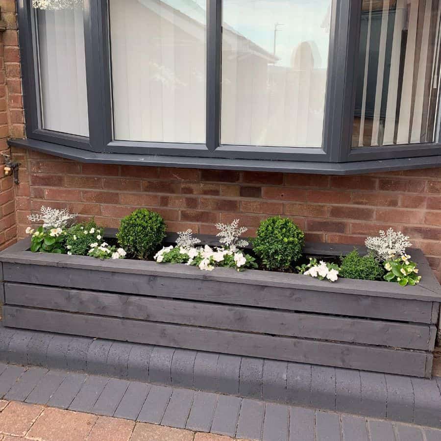 raised wood flower bed against brick wall
