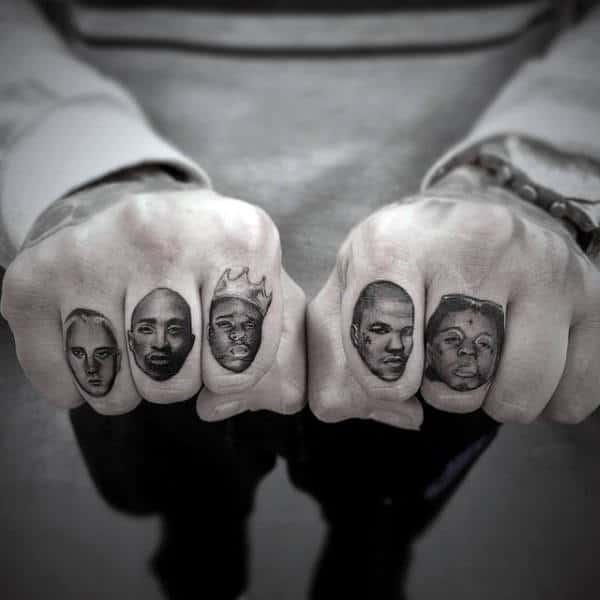 Hands with tattoos of various rapper faces on the knuckles