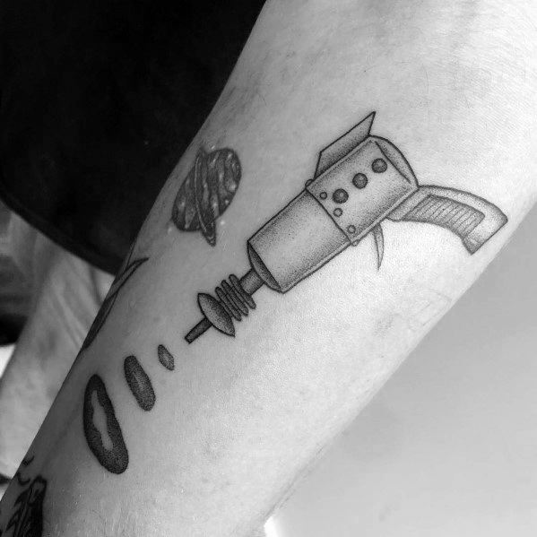 Minimalist black and grey ray gun tattoo with a simple, retro-futuristic design, featuring clean lines, subtle shading, and a space-themed touch.