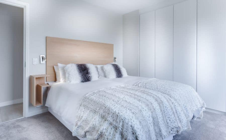 White modern bedroom with textured bedding and reach-in closet.