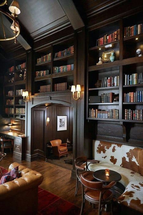 Cozy library with tall, dark wooden bookshelves, leather chairs, and warm lighting