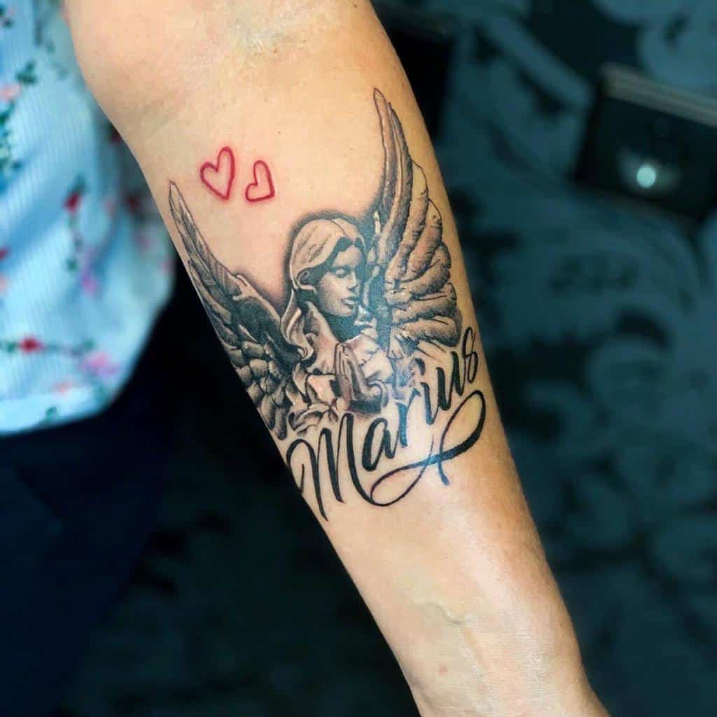 Tattoo of an angel with wings and two red hearts, above the name "Marius" and infinity symbols