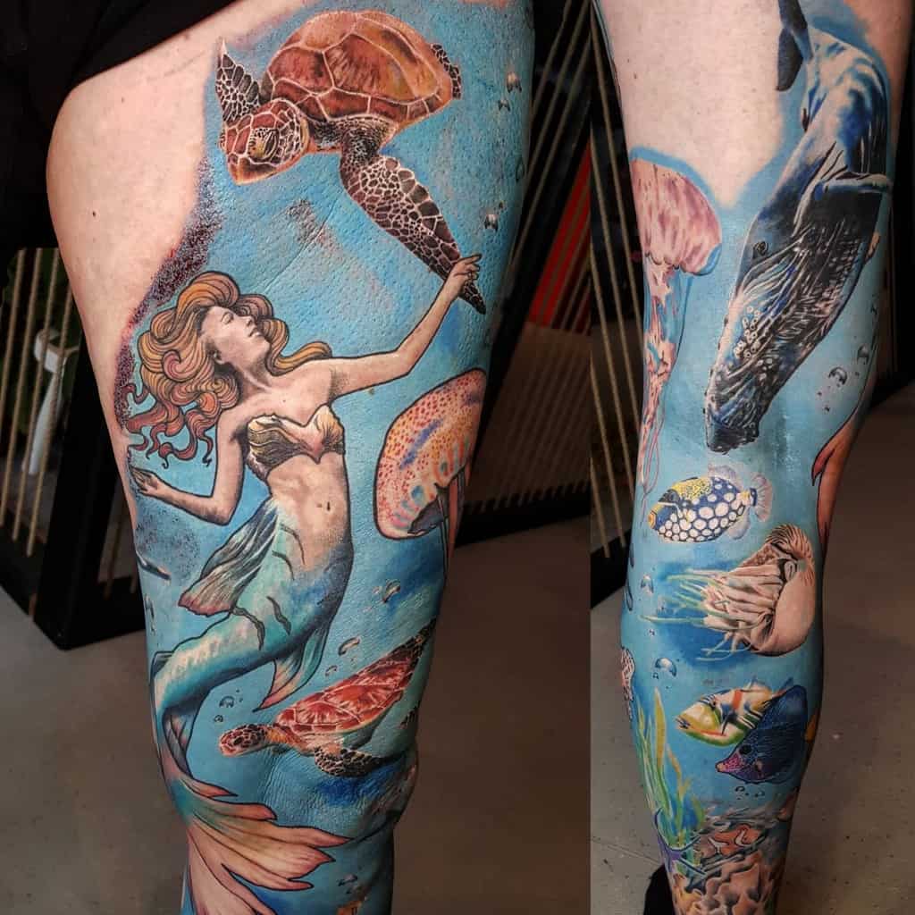Vibrant full-leg tattoo of an underwater scene featuring a mermaid, sea turtles, jellyfish, a whale, and colorful marine life.