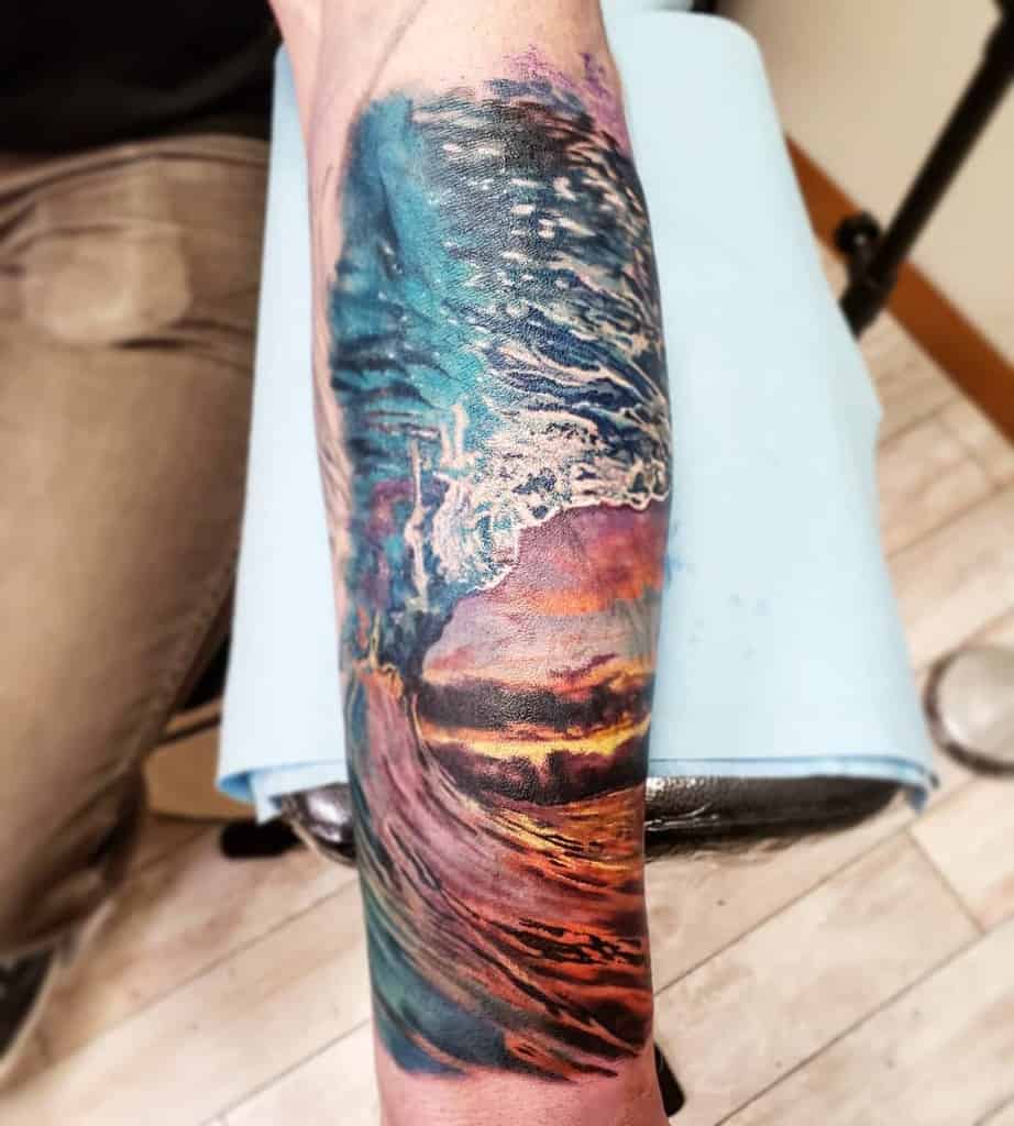 Tattoo of a vibrant ocean wave with a sunset, featuring blue, purple, and orange hues