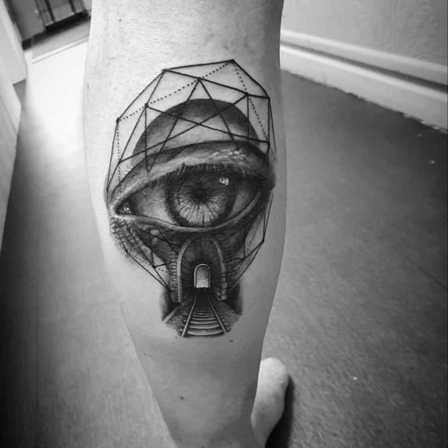 Leg tattoo featuring a surreal eye with geometric patterns, a tunnel, and train tracks, blending realism with abstract elements.