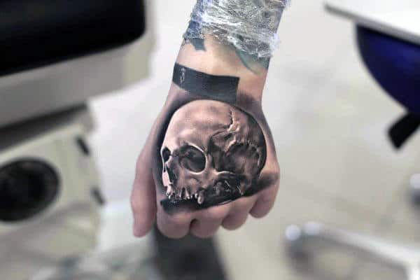 Hand with a realistic skull tattoo covering the back of the hand
